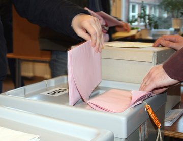 Kuvert einer Wahl wird in die Wahlurne gesteckt.