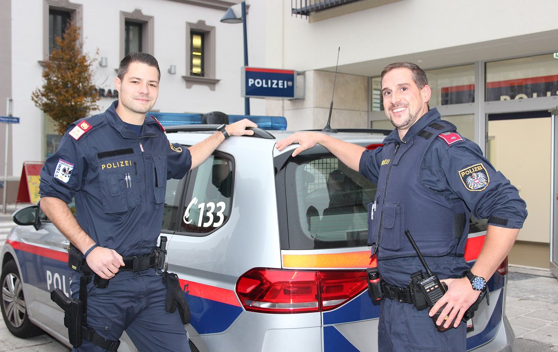 Polizeiinspektion - zwei Polizisten vor einem Polizeiauto
